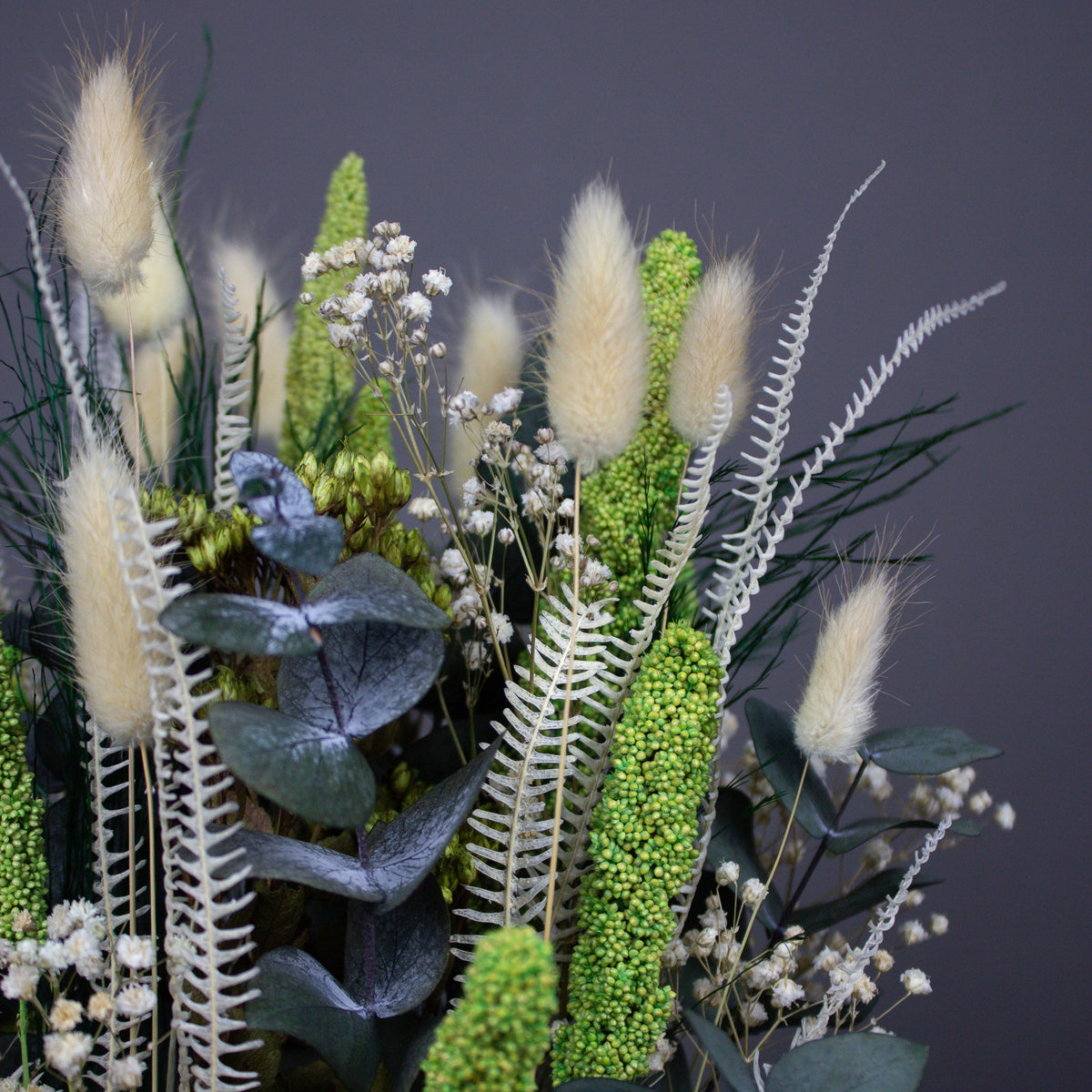 Nærbillede af en dekoration med grøn-hvide langtidsholdbare blomster.