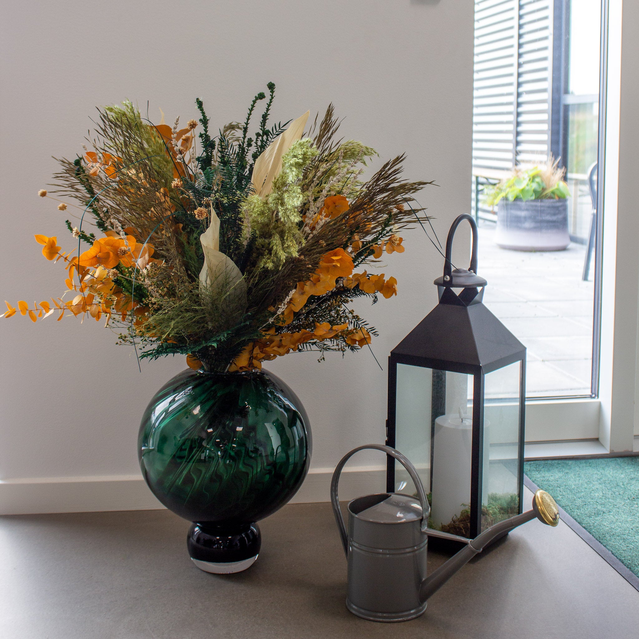 En stor efterårsinspireret blomsterbuket står ved siden af anden dekoration på gulvet i receptionen hos Living Flower-kontoret.