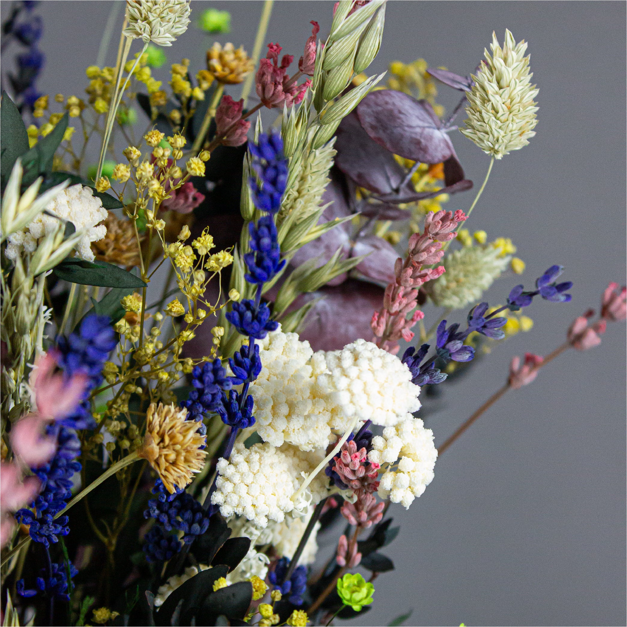 Nærbillede af en bukket med langtidsholdbare blomster i hvide, lilla, gule og grønne nuancer.