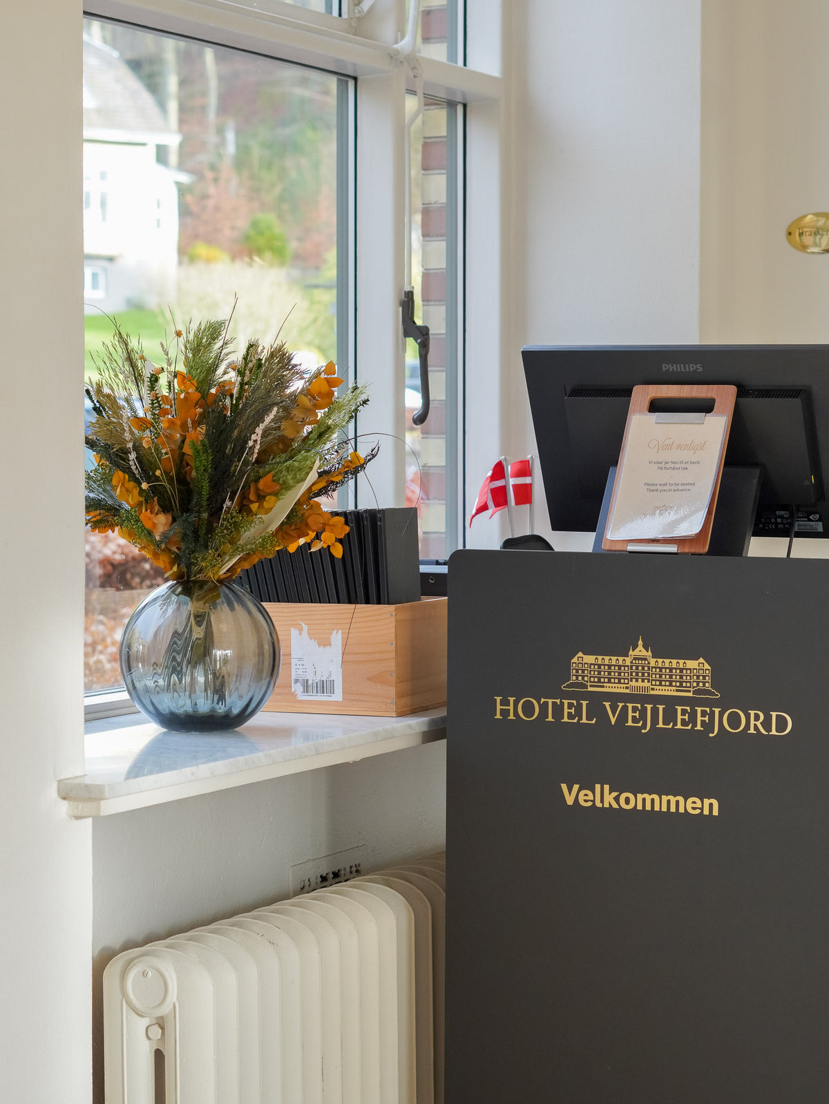 På vindueskarmen i hotellets reception står en blomsterbuket i varme efterårsnuancer.