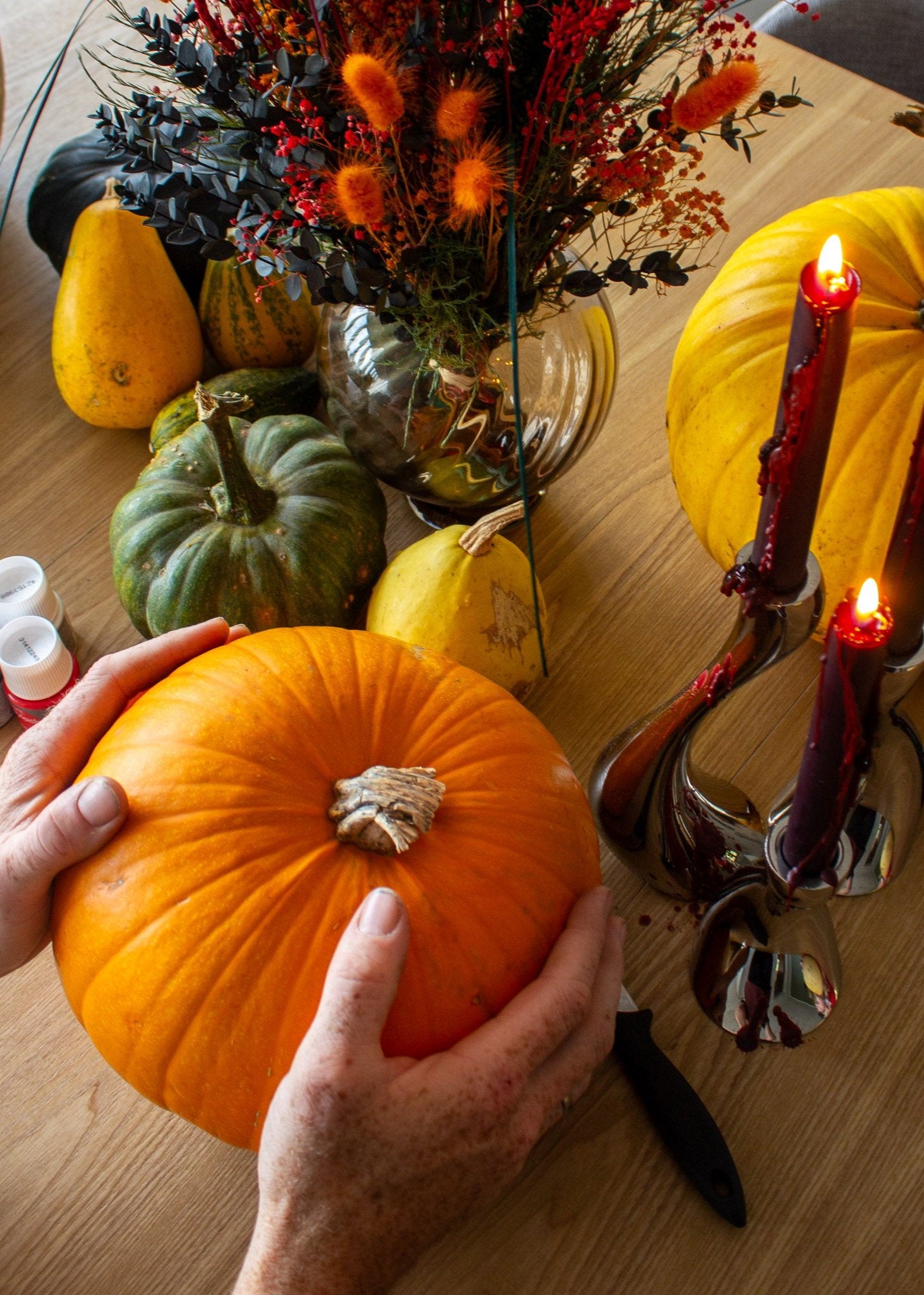 En person placerer et græskar på et Halloween-pyntet bord for at skære det ud.