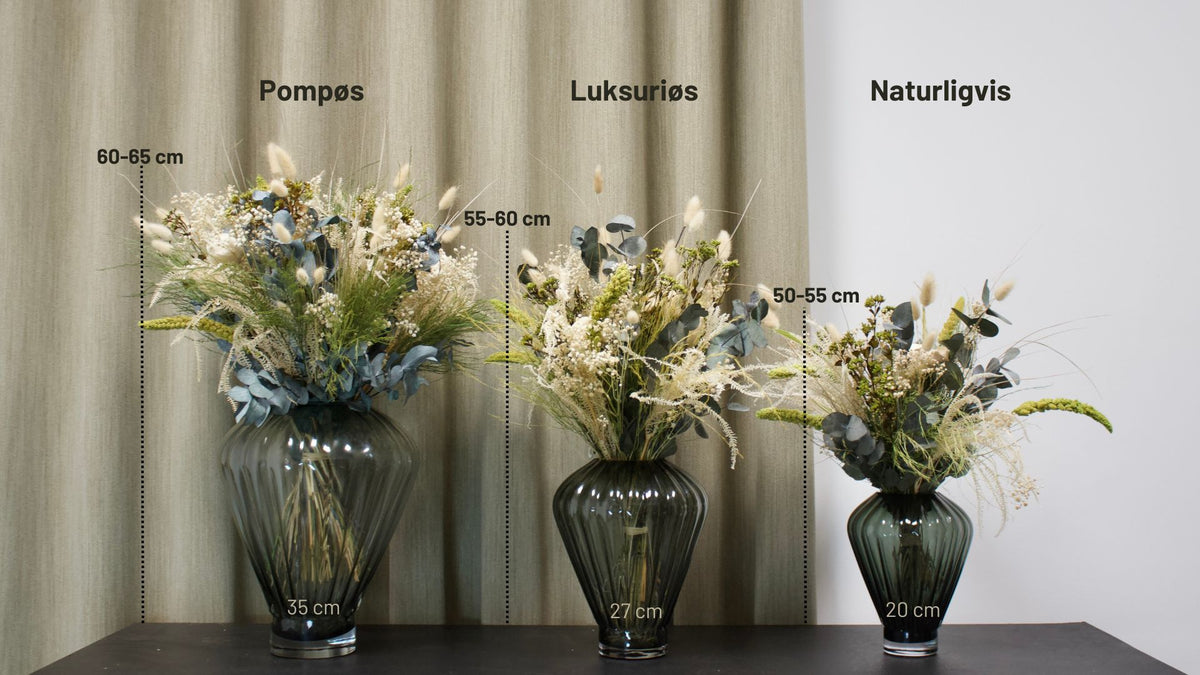 På et bord står tre blomsterbuketter i størrelserne Naturlig, Luksuriøs og Pompøs med tilhørende vaser. Størrelserne er markeret på billedet.